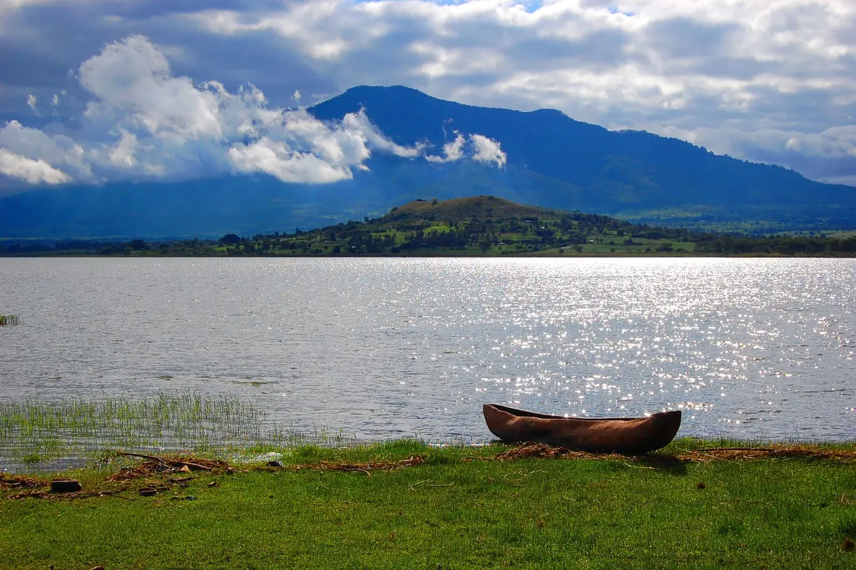 Der Babati-See mit einem Holzkanu am Ufer und Bergen im Hintergrund